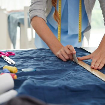 Hands of tailor drawing on fabric before sewing